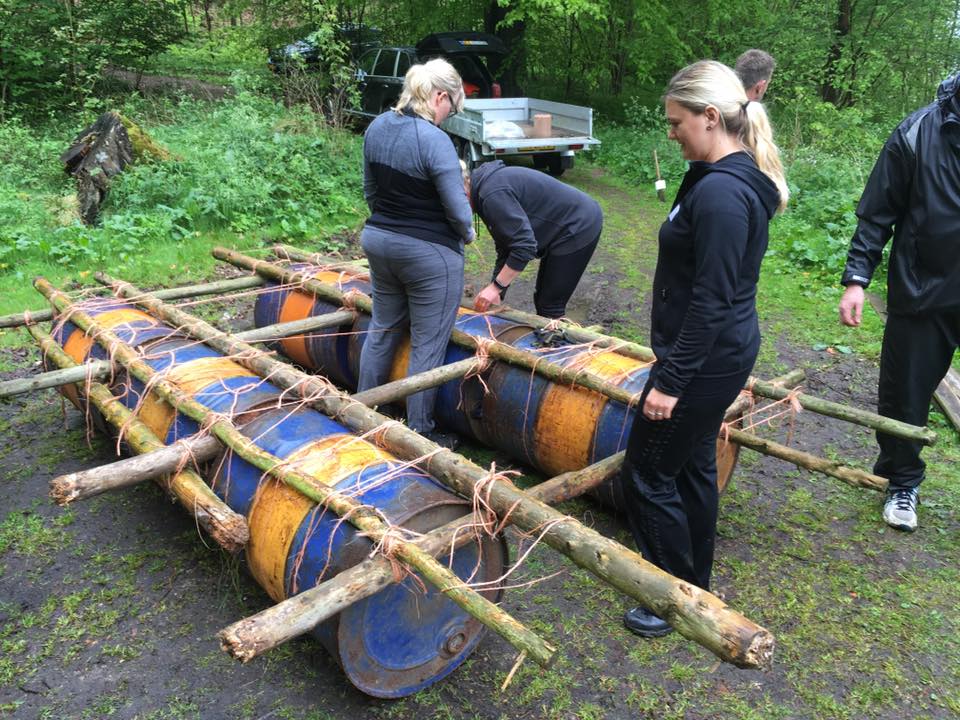 Kursister hjælper hinanden med at bygge tømmerflåde.