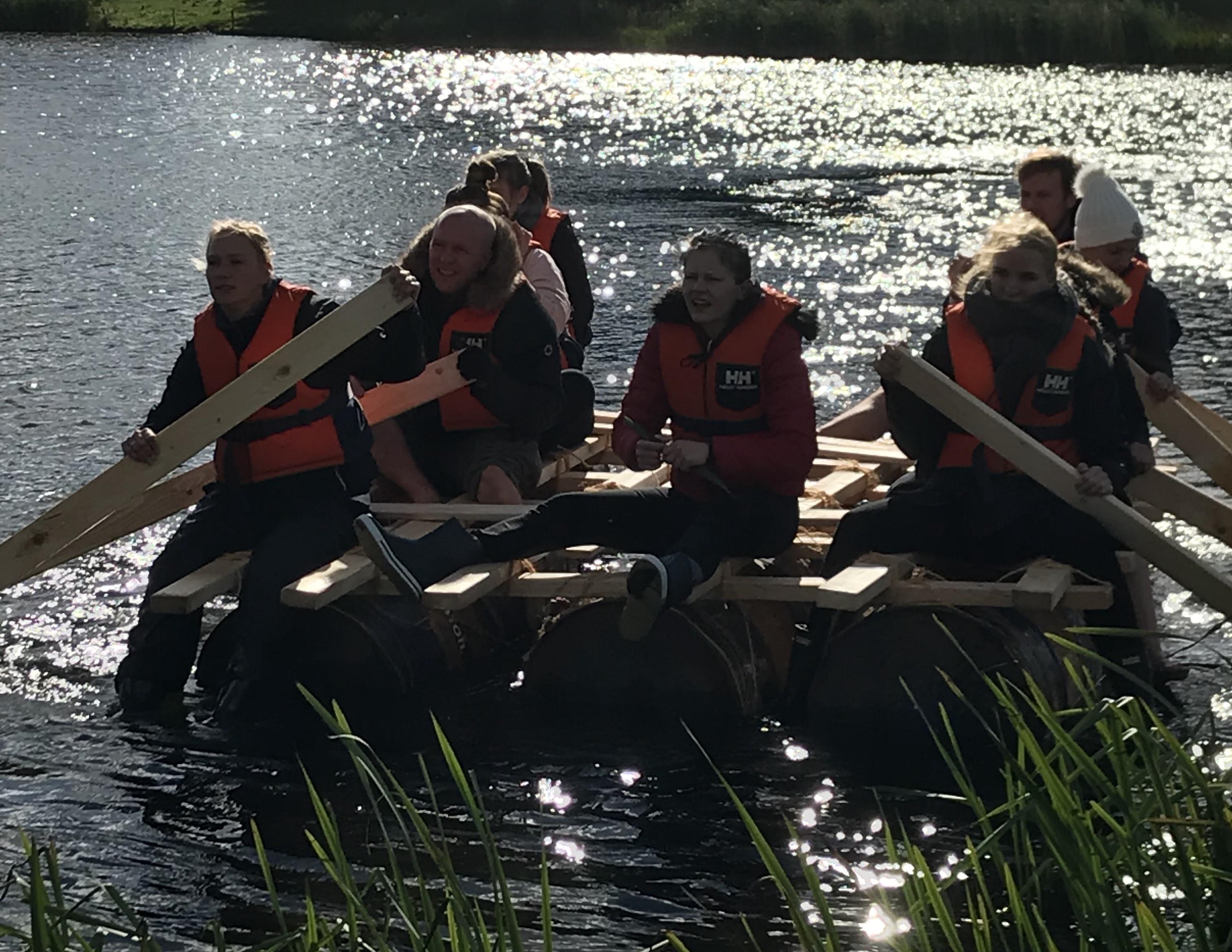 Kursister i vandet med selvkonstrueret tømmerflåde.